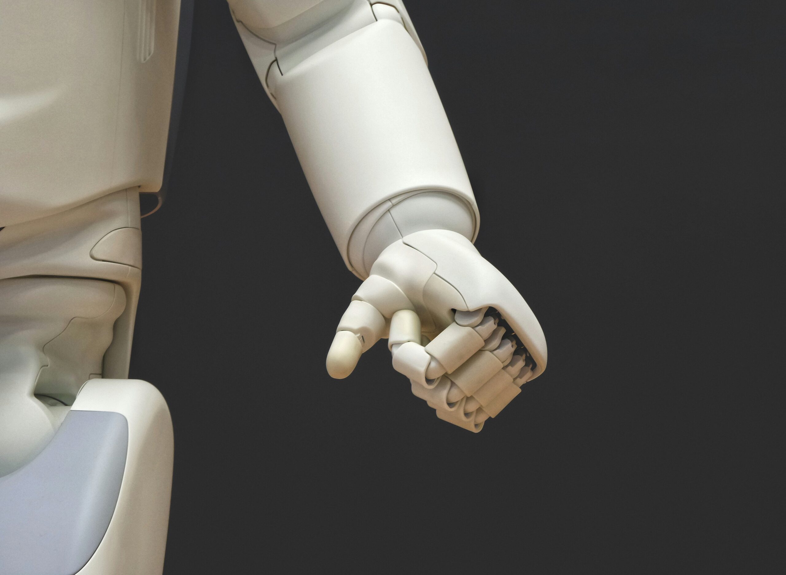 A close-up image of a white robotic hand, showcasing intricate design and technology.